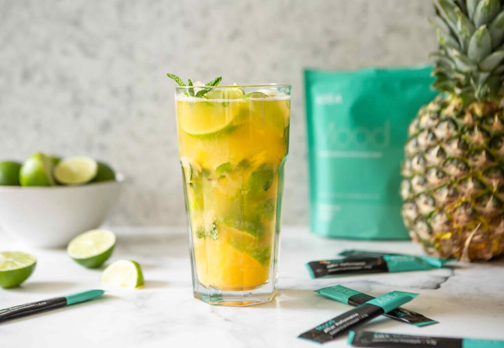 A tropical-inspired ASEA Mood refresher drink in a clear glass with fresh mint and citrus, displayed alongside ASEA Mood stick packs. The image highlights a refreshing mood drink designed to support calm and emotional balance.