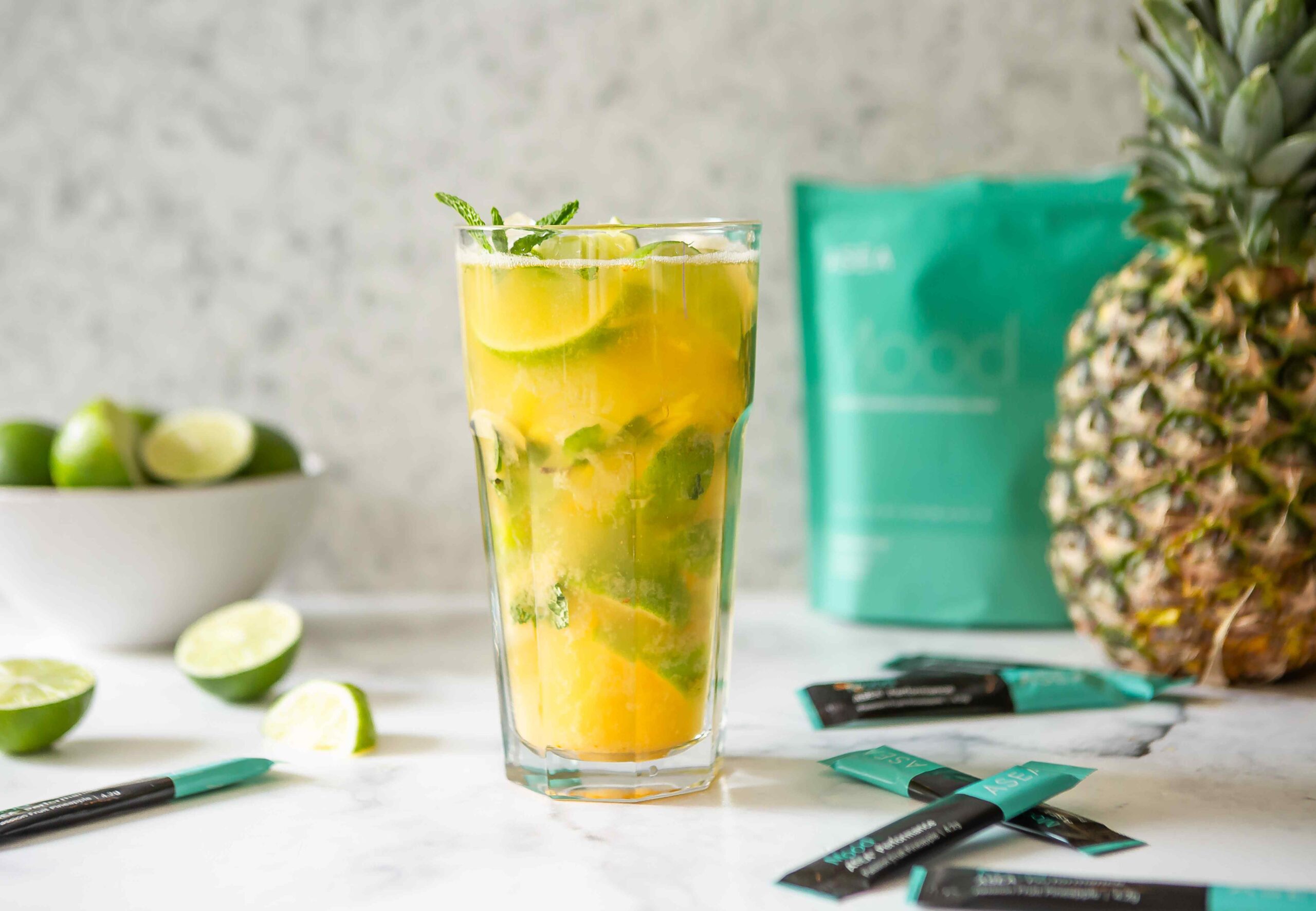 A tropical-inspired ASEA Mood refresher drink in a clear glass with fresh mint and citrus, displayed alongside ASEA Mood stick packs. The image highlights a refreshing mood drink designed to support calm and emotional balance.