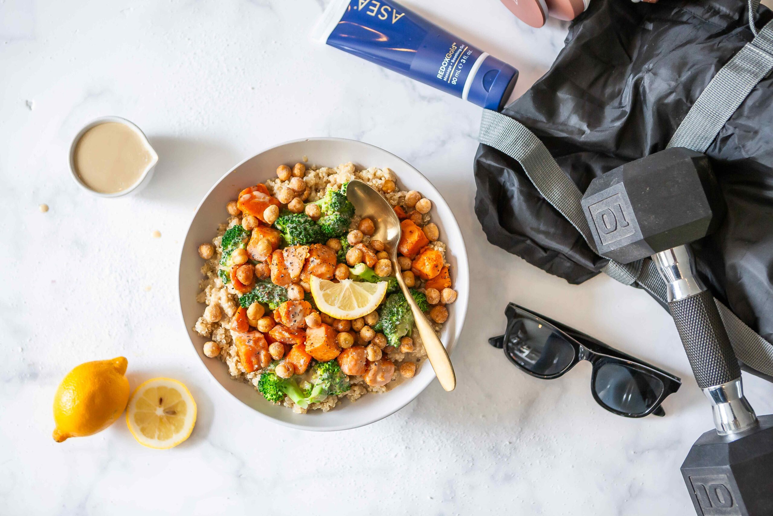 A flat lay featuring a recovery bowl alongside workout gear like a dumbbell, gym bag, and sunglasses, with REDOXGold pictured as part of the recovery routine. It reinforces the article’s message of pairing nutrition with a targeted post-workout recovery step.