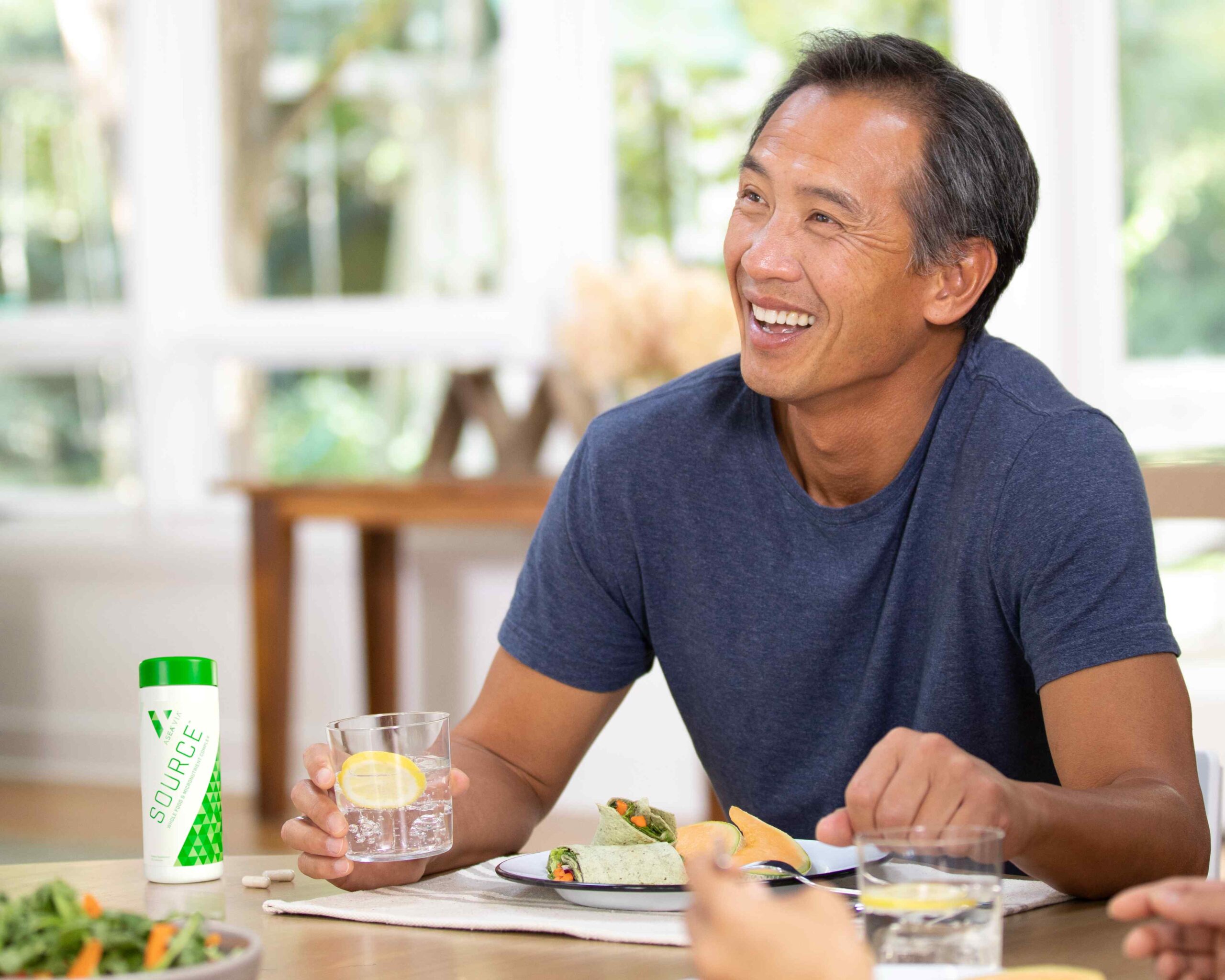 A man enjoying a healthy meal while taking biohacking supplements, reflecting a balanced lifestyle that supports cellular health and sustained energy through daily nutrition choices.