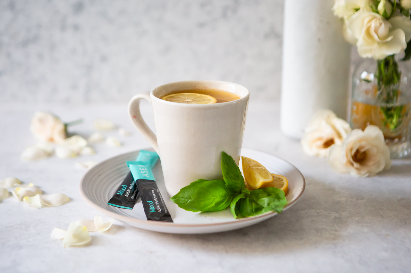 A ceramic mug filled with ASEA Mood tea is styled with lemon slices, basil, and stick packs, illustrating a simple ritual to support emotional balance and relaxation.