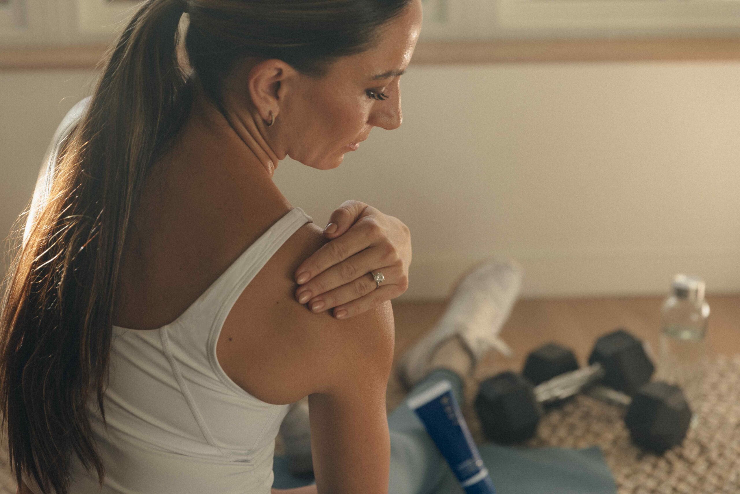 A woman focuses on post-workout recovery habits, reflecting the importance of hydration, nutrition, and rest to support muscle recovery after exercise.