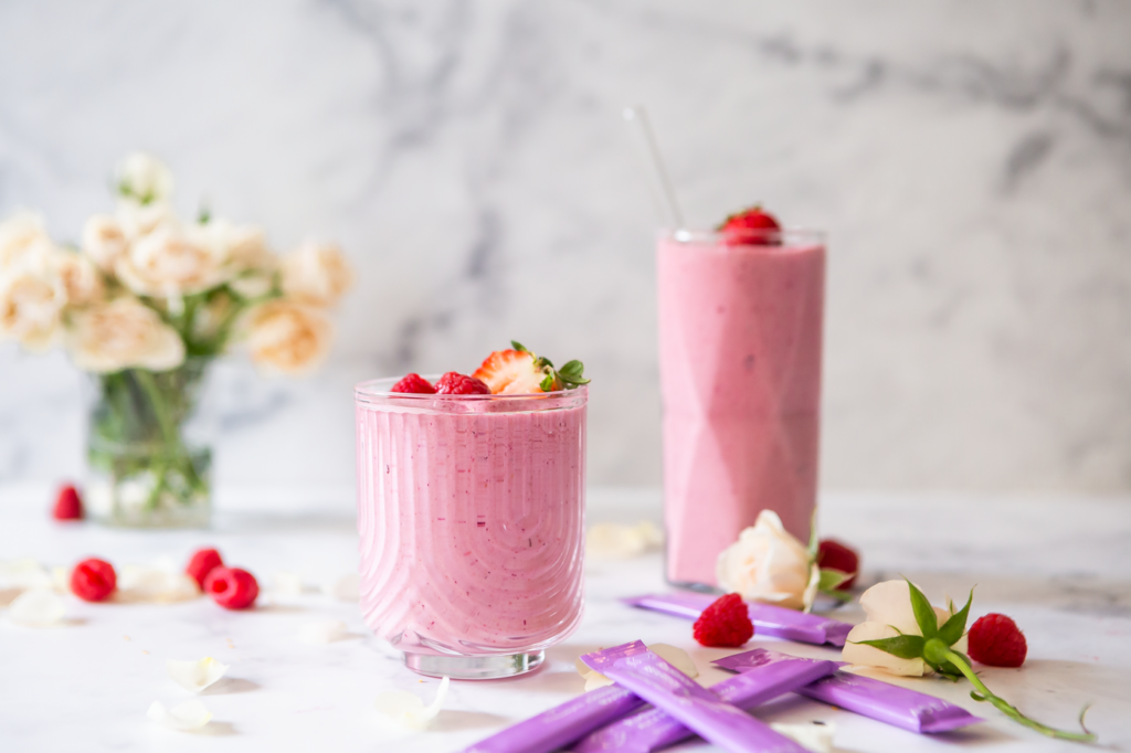 A pink collagen support smoothie made with berries and ASEA Radiance, styled on a light countertop with fresh fruit accents.