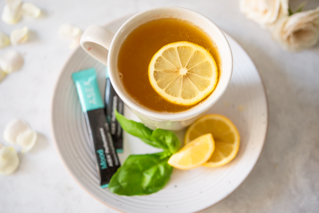 A warm cup of mood boosting tea made with chamomile, lemon, and honey sits on a saucer alongside ASEA Mood stick packs, setting the tone for a calming daily ritual.