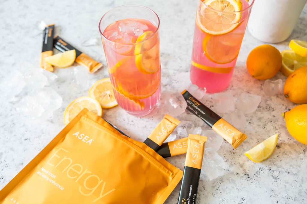 A refreshing pink lemonade drink made with ASEA Energy stick packs, served over ice with fresh lemon slices for a clean, energizing summer beverage.