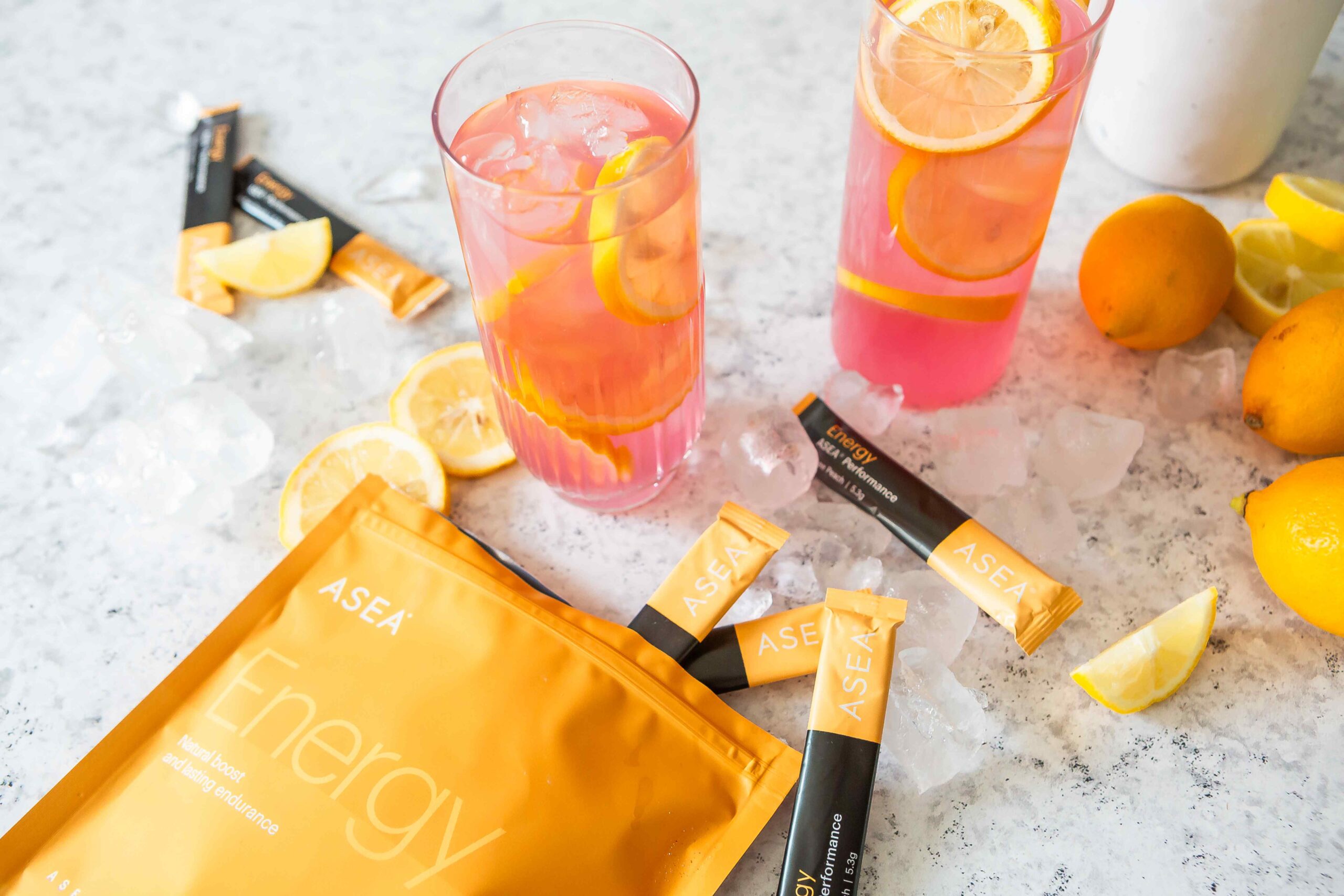 A refreshing pink lemonade drink made with ASEA Energy stick packs, served over ice with fresh lemon slices for a clean, energizing summer beverage.