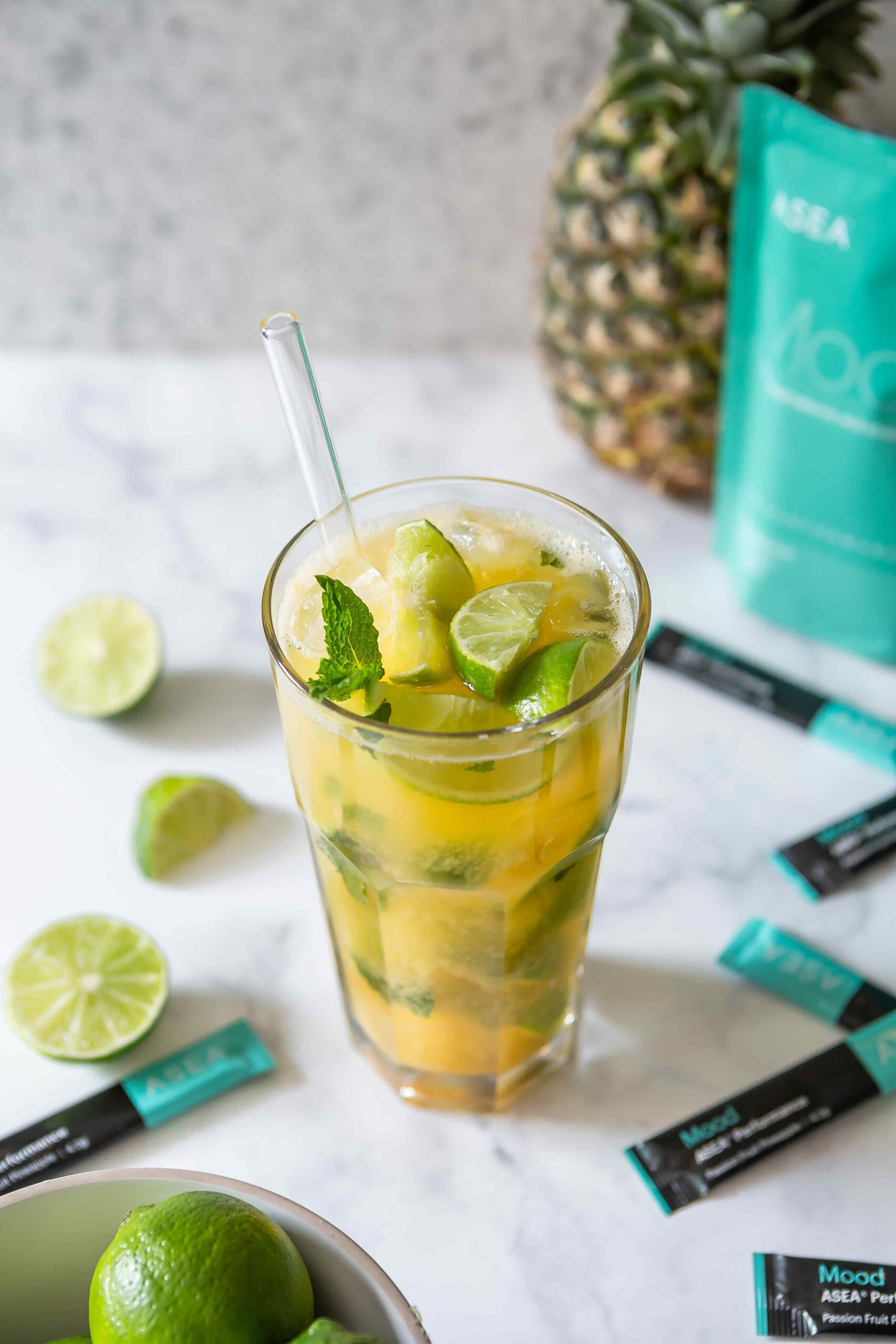 Ingredients for a tropical ASEA Mood refresher, including pineapple juice, coconut water, lime, and fresh mint. This image visually supports the recipe for a refreshing mood drink with natural antioxidants.