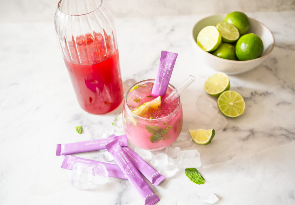Glass of Radiance Mint Lime Cooler made with fresh lime, mint, coconut water, and ASEA Radiance stick packs on ice for a refreshing summer wellness drink.